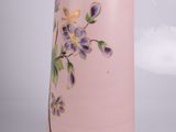 a pink vase with purple flowers painted on it