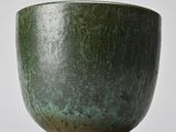 a close up of a green bowl on a white surface