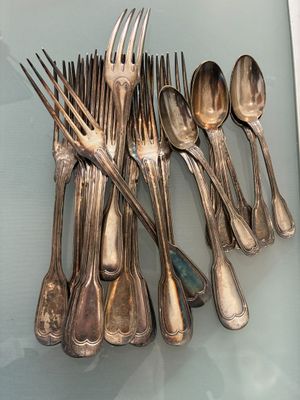 a lot of silver spoons and forks on a glass table