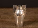 a silver vase on a wooden table with a black background