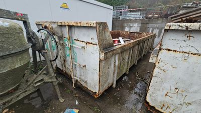 a dumpster in the middle of a dirty yard