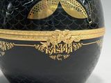 a black vase with a gold decoration on it