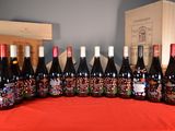 bottles of wine are lined up on a table with a red cloth