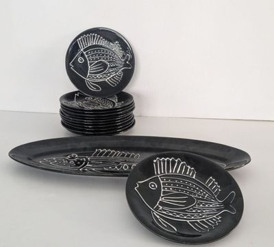 black and white plates with fish designs on them sitting on a table