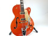 an orange electric guitar sitting on top of a stand on a white surface