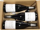 three bottles of wine are in a cardboard box on a table