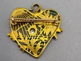 a close up of a heart shaped brooch with a stick in it