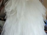 a white dress hanging on a wooden rack in a room