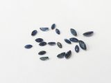 some dark blue glass beads are scattered on a white surface