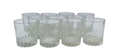 six clear glasses are lined up in a row on a white surface