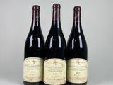 trois bouteilles de vin rouge sont posées les unes à côté des autres sur une table