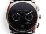 La montre est dotée d'un cadran noir et d'un bracelet en cuir noir.