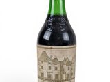 une vieille bouteille de vin posée sur une surface blanche