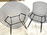 pair of black wire chairs sitting on top of a white sheet