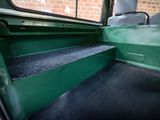 a green bus with a black carpet on the side of the bus