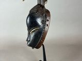 a close up of a wooden mask on a black stand