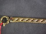a close up of a gold bracelet with a red string