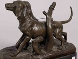bronze statue of two dogs on a rock with a bird in its mouth