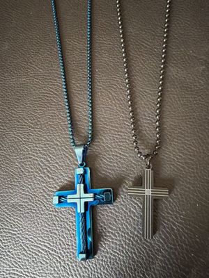 two cross pendants on a leather surface