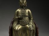 une statue en bronze représentant un Bouddha assis sur un rocher