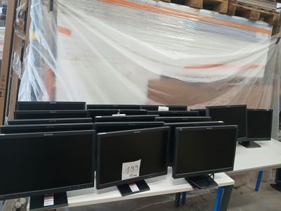 de nombreux écrans d'ordinateur posés sur une table dans un entrepôt