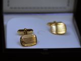 two pairs of gold cufflinks in a box on a white surface