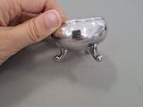 a hand that is holding a silver object on a table