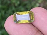 quelqu'un tient dans sa main une pierre précieuse jaune et blanche