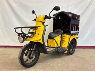 a yellow scooter that is parked in front of a white wall