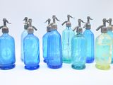 six bouteilles en verre bleues sont alignées sur une surface blanche