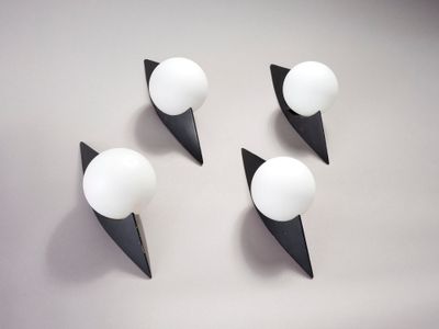 trois appliques murales noires et blanches fixées sur un mur blanc