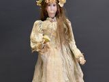an antique doll is standing on top of a piece of luggage