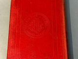 an old red book sitting on top of a white table