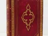 an old red book with a gold design on the cover
