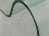 the curved glass table top is made of glass and has a black metal frame