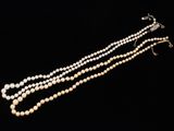 a close up of a necklace with pearls on a black background