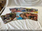 a lot of magazines on a bed with a white sheet