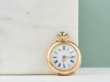 an image of a gold pocket watch sitting on top of a marble block