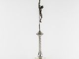 a silver statue of a person on a pole with a rope