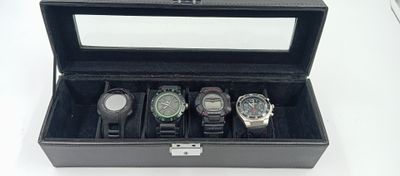 quatre montres dans un coffret noir posées sur une table blanche