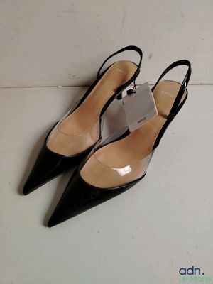 une paire de chaussures noires à talons hauts posée sur un sol blanc