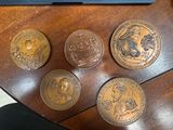 several coins sitting on top of a wooden table next to a laptop