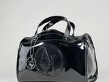 the black handbag is sitting on a white surface with a chain around it
