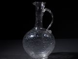 a clear glass vase with a handle on a table