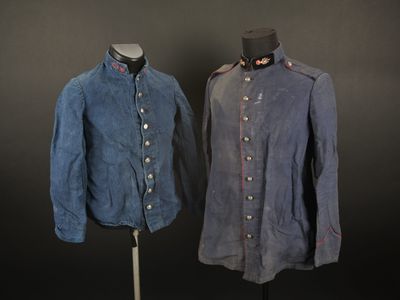 deux uniformes militaires posés sur un mannequin, sur fond noir