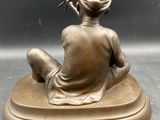 bronze statue of a woman sitting on a base with a gun