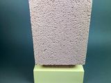 a close up of a block of cement on a green surface