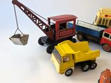 a toy truck with a crane attached to it next to other toy vehicles