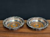 two silver plated bowls on a wooden table with a black background