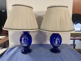 pair of blue glass lamps on a blue table with a white lamp shade